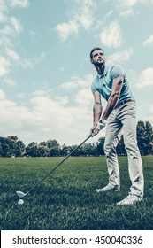 Preparing To Strike. Low Angle View Of Young Man Playing Golf While Standing On Green