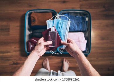 Preparing for travel in new normal. Man packing passport, face masks and hand sanitizer. Themes personal protection and flight rules during coronavirus pandemic. - Powered by Shutterstock