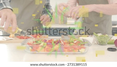 Preparing two cooks arranging sliced veg, pouring oil in home kitchen with glass dish and aprons. Vegetables, couple, culinary, cooking, colorful, prep, oliveoil