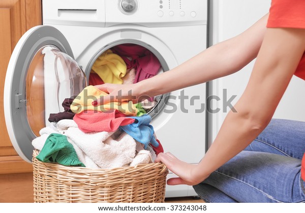 Preparing the wash cycle. Washing machine, hands\
and clothes.