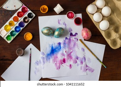 Preprimary painting of Easter Eggs, Brushes, Paints, Eggs on the Dark Wooden Table. Easter concept.