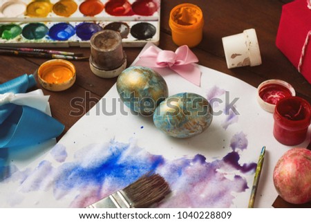 Preprimary painting of Easter Eggs, Brushes, Paints, Eggs on the Dark Wooden Table. Easter concept.