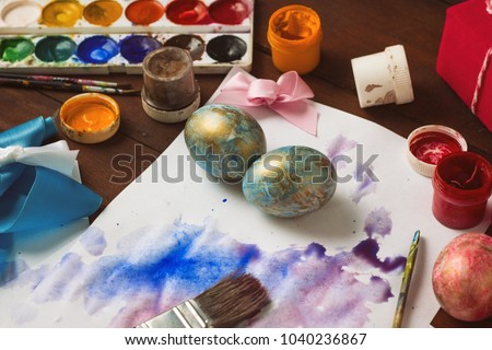 Preprimary painting of Easter Eggs, Brushes, Paints, Eggs on the Dark Wooden Table. Easter concept.