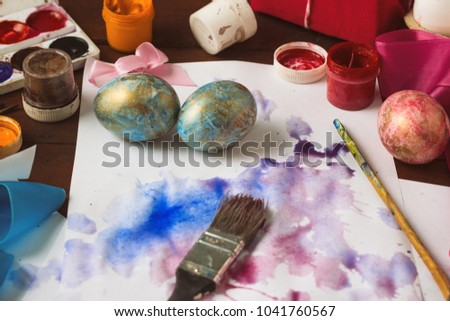 Preprimary painting of Easter Eggs, Brushes, Paints, Eggs on the Dark Wooden Table. Easter concept.