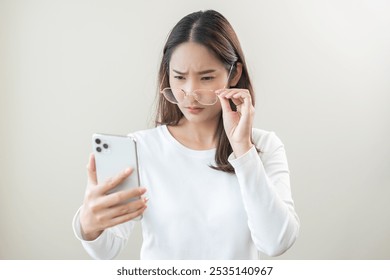 Presbyopia, Hyperopia middle aged asian woman holding eyeglasses problem with vision blurred ,trying to read text message from smart mobile phone screen, eye disease of old, eyesight farsightedness.