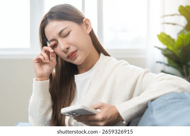 Presbyopia, Hyperopia middle aged asian woman hand rubbing her eye with vision blurred ,girl trying to read text message from smart mobile phone screen, eye disease of old, eyesight farsightedness.