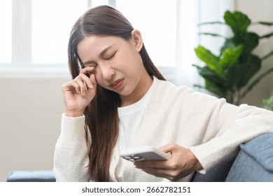 Presbyopia, Hyperopia middle aged asian woman hand rubbing her eye with vision blurred ,girl trying to read text message from smart mobile phone screen, eye disease of old, eyesight farsightedness.