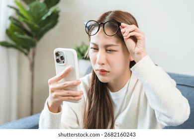 Presbyopia, Hyperopia middle aged asian woman holding eyeglasses problem with vision blurred ,trying to read text message from smart mobile phone screen, eye disease of old, eyesight farsightedness.