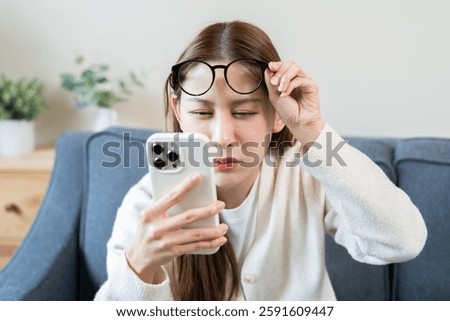 Presbyopia, Hyperopia middle aged asian woman holding eyeglasses problem with vision blurred ,trying to read text message from smart mobile phone screen, eye disease of old, eyesight farsightedness.