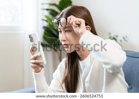 Presbyopia, Hyperopia middle aged asian woman holding eyeglasses problem with vision blurred ,trying to read text message from smart mobile phone screen, eye disease of old, eyesight farsightedness.