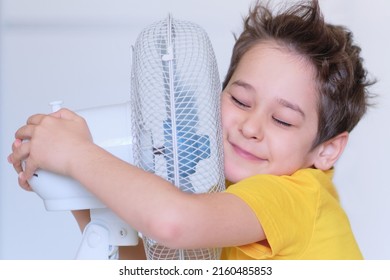 Preschool Boy Cooling In Front Of Fan. Little Child Refreshing From Heat In Front Of Small Fan At Home. Cute Small Kid Play With Ventilator Blowing Cool Wind Alone.