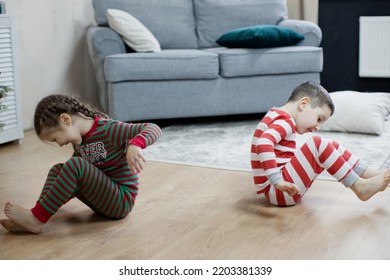 Preschool Boy And Girl In Christmas Pyjamas Sitiing On A Floor