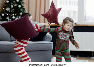 Preschool Boy And Girl In Christmas Pyjamas Fighting With Pillows At Christmas Interior