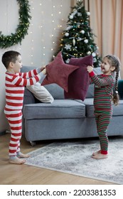 Preschool Boy And Girl In Christmas Pyjamas Fighting With Pillows At Christmas Interior