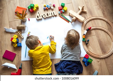 Preschool boy and girl play on floor with educational toys - blocks, train, railroad, plane. Toddler kids drawing. Toys for preschool and kindergarten. Children at  home or daycare. Top view - Shutterstock ID 1008016099