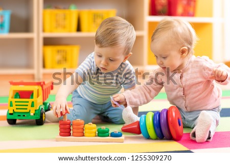 Preschool boy and girl playing on floor with educational toys. Children toddlers at home or daycare.