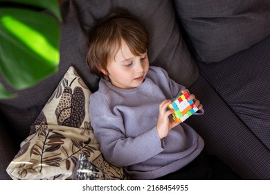 Preschool boy playing logic game at home, smart child solving puzzle cube, early development concept.