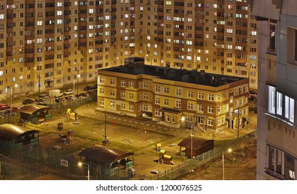 Preschool Building Exterior With Playground On Evening.