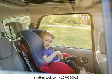 Preschool cute 3-4 years old boy sitting in safety car seat and crying during family travel by car, bad mood, negative emotion, upbringing and family concept, summer outdoor.