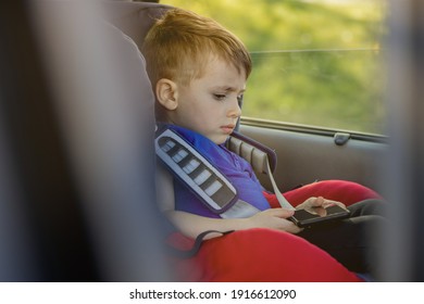 Preschool cute 3-4 years old boy sitting in safety car seat and crying during family travel by car, bad mood, negative emotion, upbringing and family concept, summer outdoor