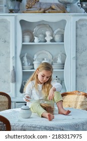 A Preschool Girl Holds A Cookie Jar In A Vintage Dining Room. Retro Interior.