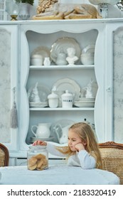 A Preschool Girl Holds A Cookie Jar In A Vintage Dining Room. Retro Interior.