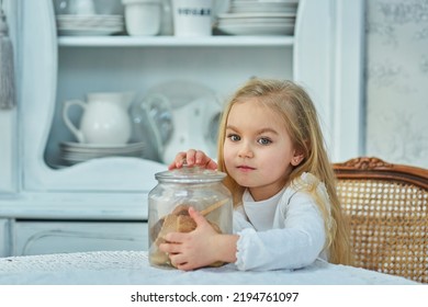 A Preschool Girl Holds A Cookie Jar In A Vintage Dining Room. Retro Interior.