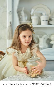 A Preschool Girl Holds A Cookie Jar In A Vintage Dining Room. Retro Interior.