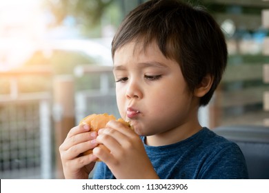 Preschool Kid Boy Eats Hamburger Sitting In Nursery Cafe,Cute Happy Boy Eating Hamburger Sitting In The Restaurant,Healthy Child Eating Delicious Homemade Burger,
