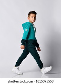 Preschool or school little boy with stylish coiffure wearing tracksuit and sneakers walking and looking at camera isolated on grey studio background. Children sport fashion clothing advertisement - Shutterstock ID 1815395558