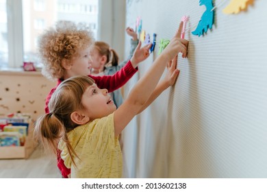 Preschool Students Playing In Kindergarten With Color Dinosaur Figures