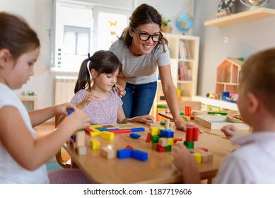 Preschool teacher with children playing with colorful wooden didactic toys at kindergarten - Shutterstock ID 1187719606