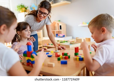 Preschool teacher with children playing with colorful wooden didactic toys at kindergarten - Shutterstock ID 1187719609