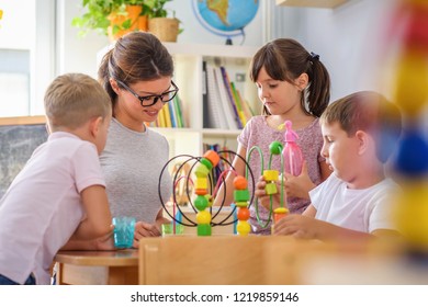 Preschool teacher with children playing with colorful wooden didactic toys at kindergarten - Shutterstock ID 1219859146