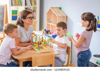 Preschool teacher with children playing with colorful wooden didactic toys at kindergarten - Shutterstock ID 1219859155