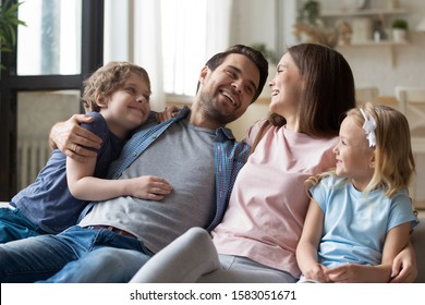 Preschooler adorable kids and their parents resting sitting on couch in living room, couple and children spend weekend together laughing enjoy communication, happy family portrait and new home concept
