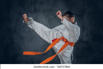 Preschooler boy dressed in a white karate kimono with orange belt.
