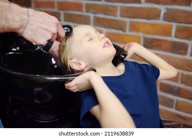 Preschooler Boy Getting Haircut In Barbershop. Children Hairdresser Washing Hair For Child. Cutting Hair For Kids. Services Of A Professional Stylist.