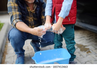 Preschooler Boy Helping His Father Washing Family Car. Little Dad Helper. Family With Children Spends Time Together In The Backyard