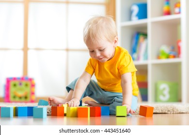 Preschooler Child Playing With Colorful Toy Blocks. Kid Playing With Educational Wooden Toys At Kindergarten Or Day Care Center. Toddler In Nursery Room.