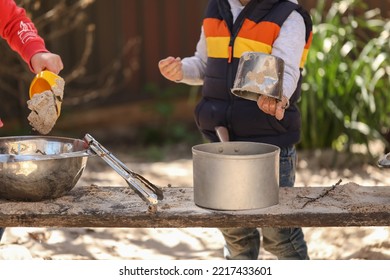 Preschooler Children Playing In Sandpit Making Mud Pies At Kindergarten