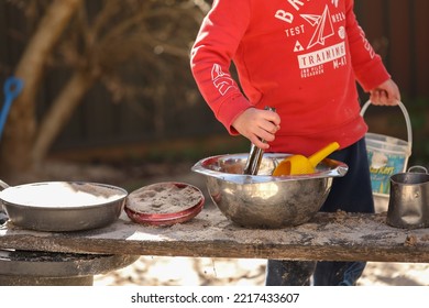 Preschooler Children Playing In Sandpit Making Mud Pies At Kindergarten