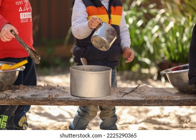 Preschooler Children Playing In Sandpit Making Mud Pies At Kindergarten