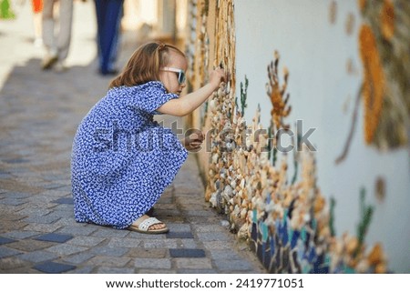Preschooler girl discovering art decorations made from shells and pebbles on walls in Ile Penotte, Les Sables d'0lonne of the department of Vendee, Pays de la Loire, France