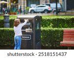 Preschooler girl gathering litter on the street of Helsinki, Finland and putting it in litterbox.