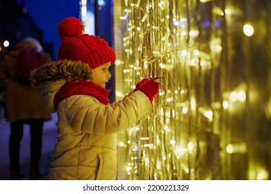 Preschooler Girl Looking At Window Glass Of Large Department Store Decorated For Christmas. Child Enjoying Holiday Season In Paris, France