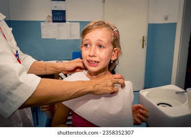 Preschooler, scared and crying cute little child is sitting on mom's lap at dentist office, preparing for removing milk tooth. - Powered by Shutterstock