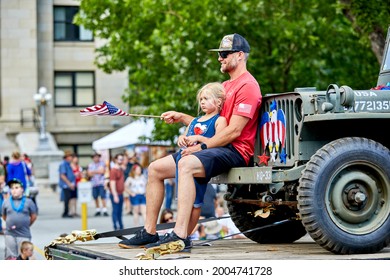 Prescott, Arizona, USA - July 3, 2021: Participants sitting on the front of an old military jeep on a float in the 4th of July parade