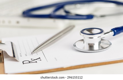 Prescription Form Clipped To Pad Lying On Table With Stethoscope And Silver Pen. Medicine Or Pharmacy Concept. Empty Medical Form Ready To Be Used