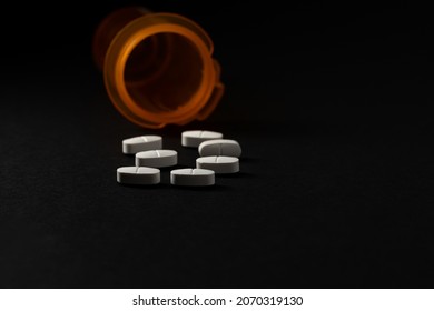 Prescription pain pills and medication bottle. Low key on black background. Concept of painkiller addiction, drug abuse, suicide, and opioid crisis